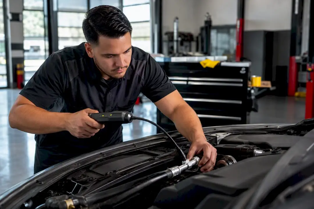 Technician inspecting vehicle AC hose connection